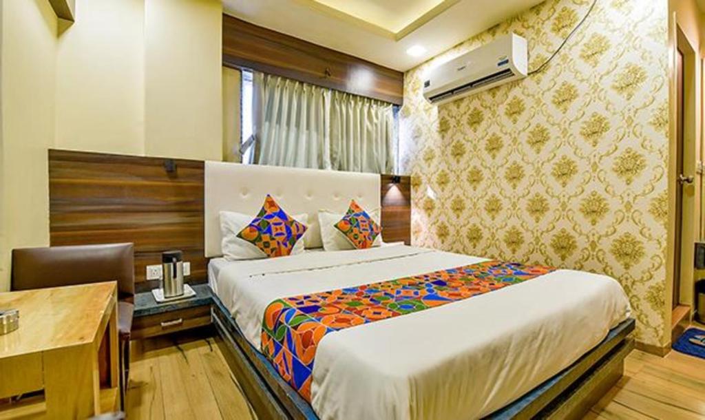 a bedroom with a large bed with a desk and a desk at FabHotel Raj Palace I in Vadodara