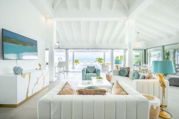 una sala de estar blanca con un sofá blanco y sillas en La Perla Bianca - 1 BR Beachfront Luxury Villa offering utmost privacy en Les Terres Basses
