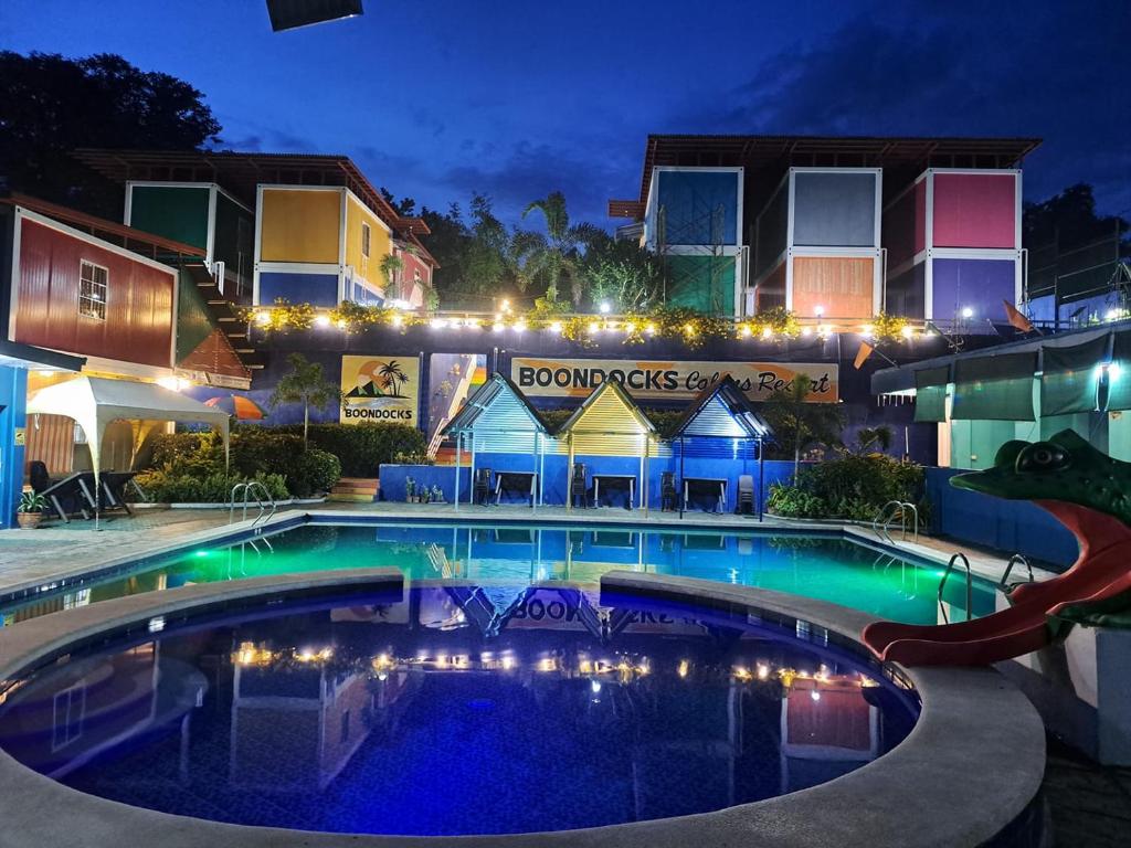 RedDoorz @ Boondocks Cabins Resort في Dalumpinas Oeste: مسبح امام مبنى في الليل