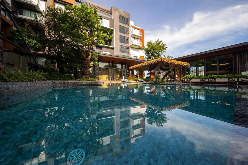 a swimming pool in front of a building at Richmann Resort Hotel Hatyai in Hat Yai