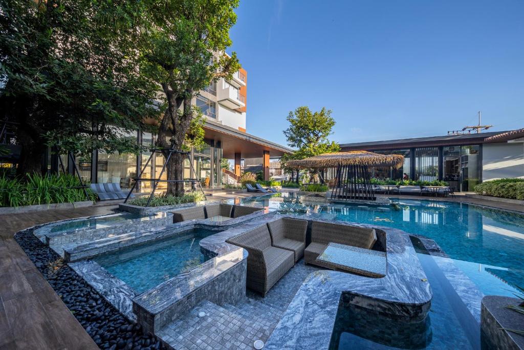 a swimming pool with a seating area in a building at Richmann Resort Hotel Hatyai in Ban Kohong