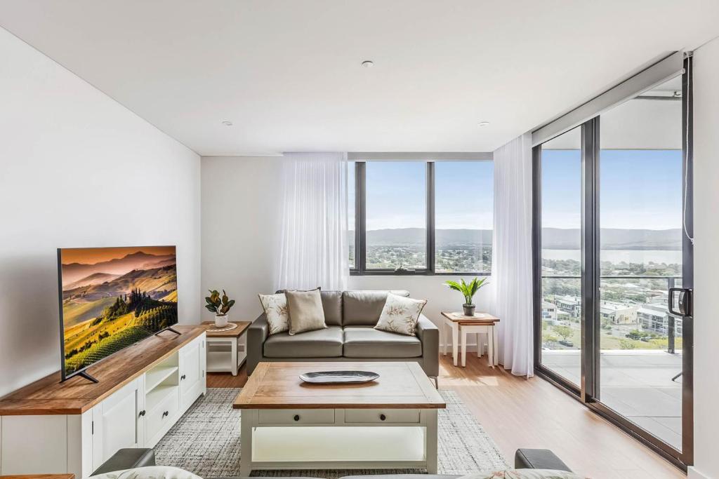 uma sala de estar com um sofá e uma grande janela em Shellharbour Lakeview Apartment em Barrack Point