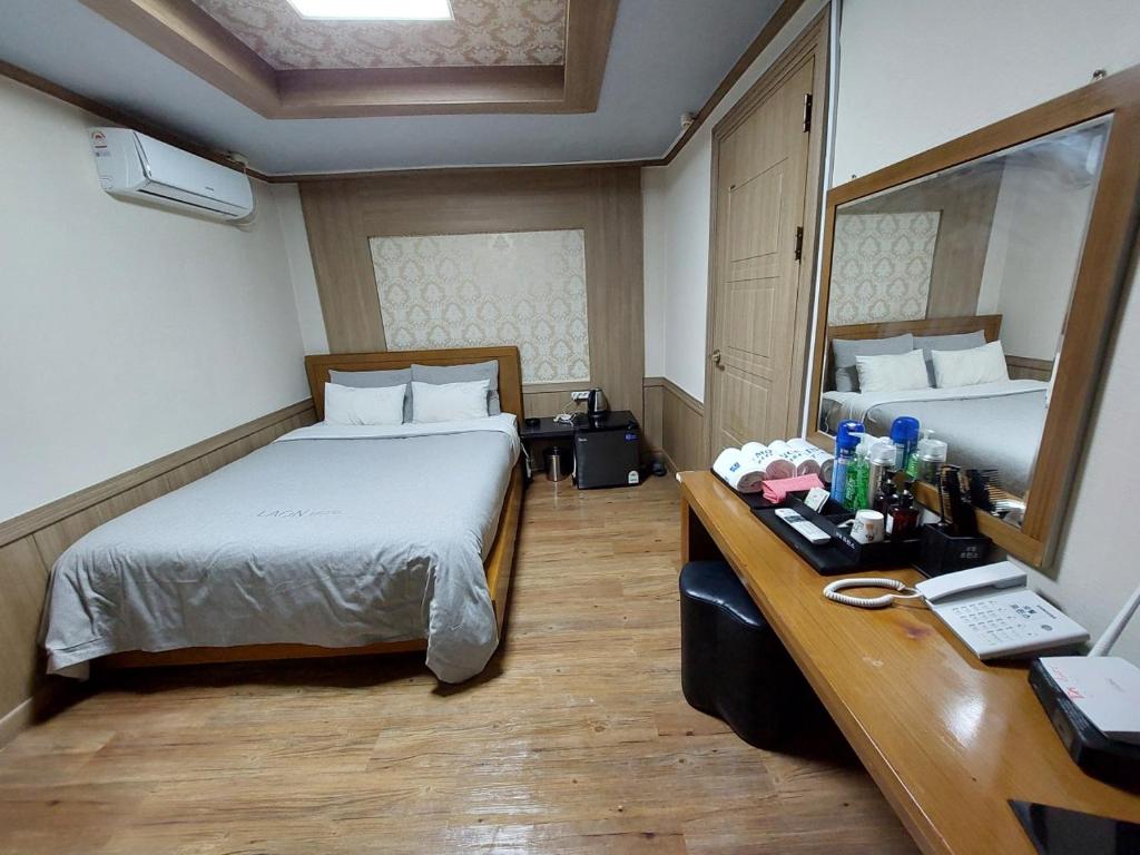 a hotel room with a bed and a desk with a mirror at Prince Motel in Busan