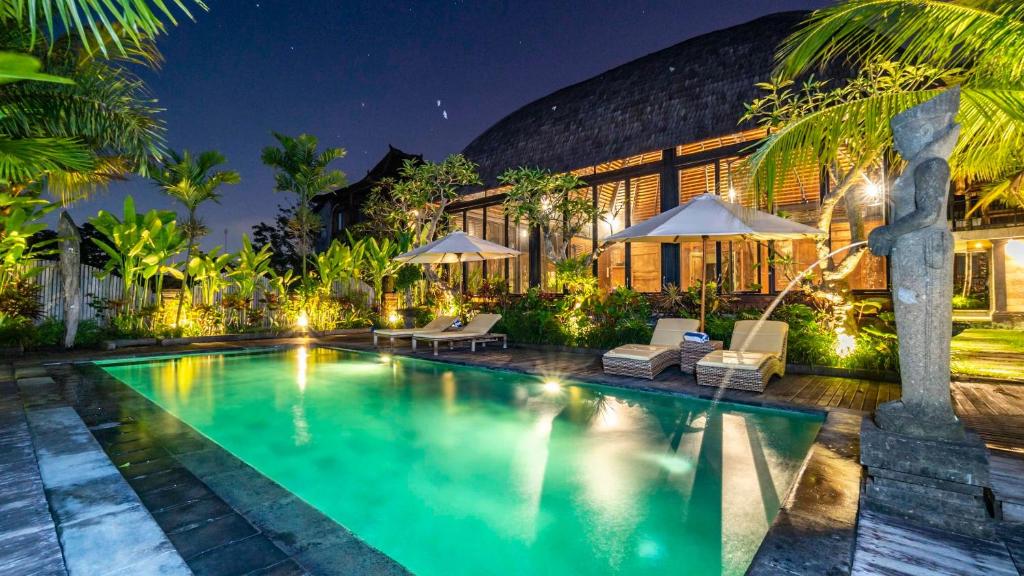 eine Villa mit einem Pool in der Nacht in der Unterkunft Picturesque Private Joglo Villa Near Monkey Forest in Ubud