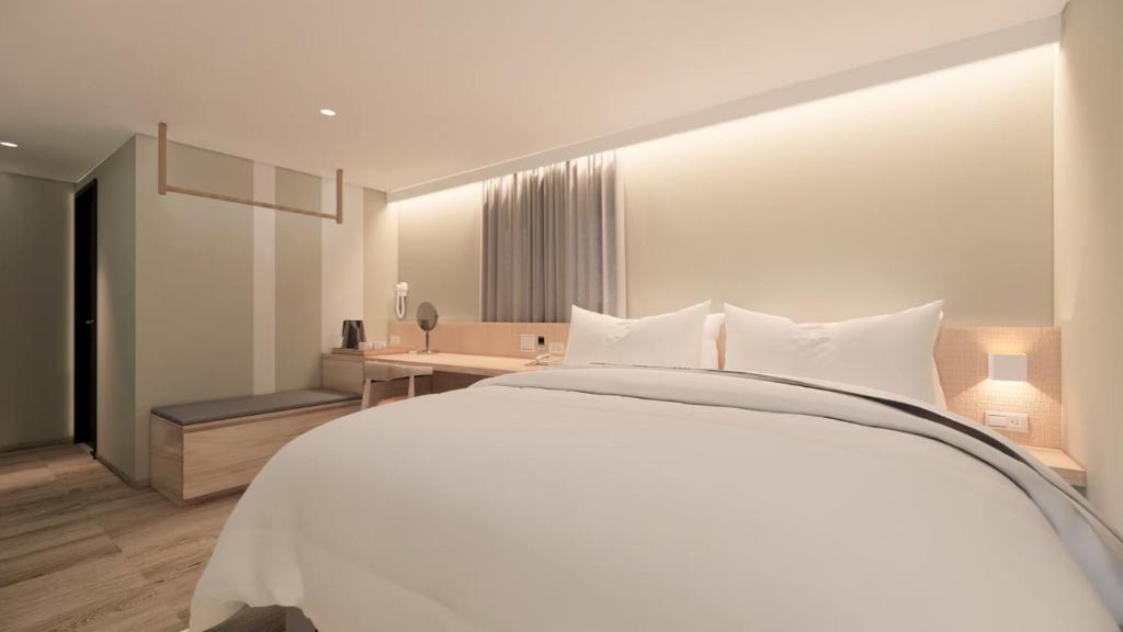 um quarto com uma grande cama branca e uma secretária em Ta Lee Hotel em Tainan