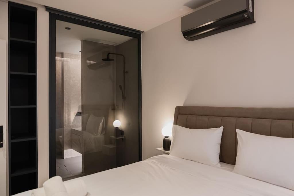 een slaapkamer met een wit bed en een glazen douche bij ID Residences 203 in Volos
