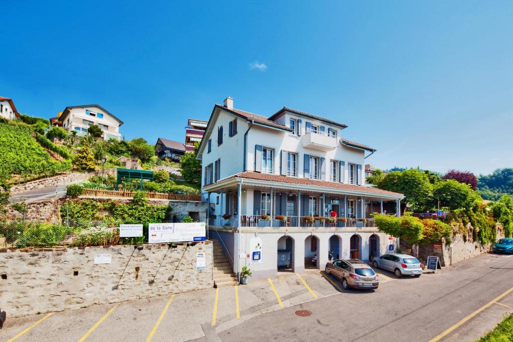 une grande maison blanche sur le côté d'une colline dans l'établissement Auberge de la Gare, à Grandvaux