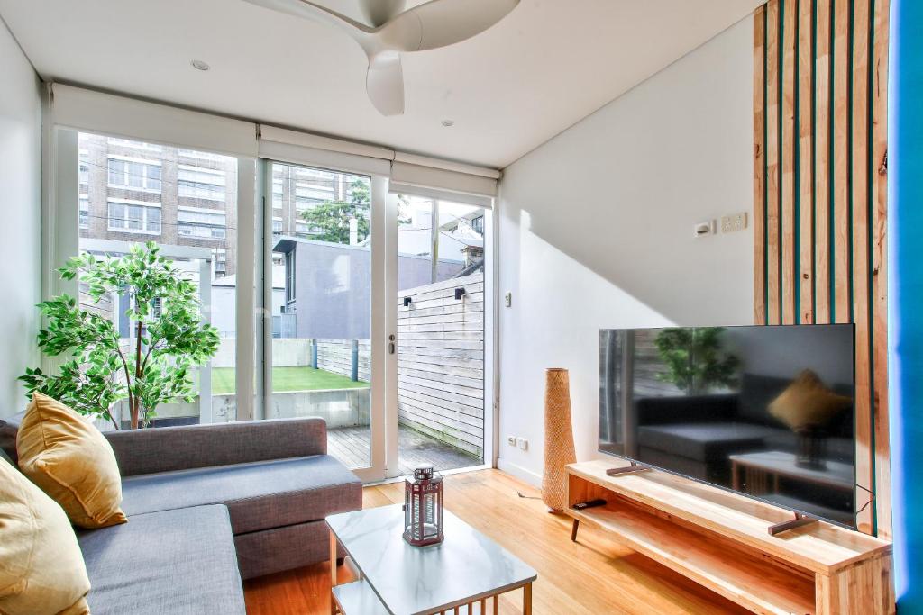 a living room with a couch and a large tv at Astounding 3 Bedroom House Surry Hills 2 E-Bikes Included in Sydney