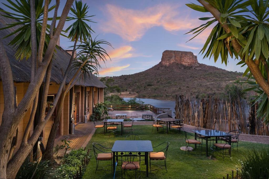 a resort with tables and chairs with a mountain in the background at Entabeni Mountain Lodges in Golders Green