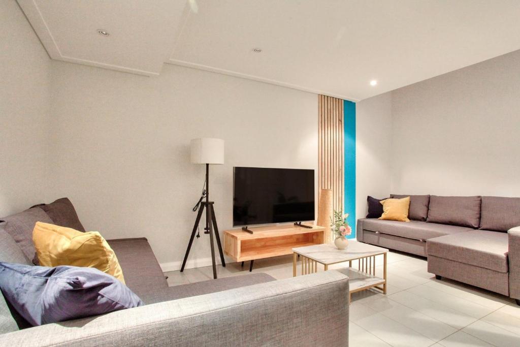 sala de estar con sofá y TV de pantalla plana en City Center 2 Bedroom House Pyrmont 2 E-Bikes Included, en Sídney