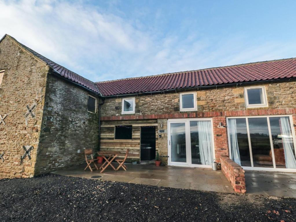 a brick house with a patio in front of it at Hawthorn Cottage in Scarborough