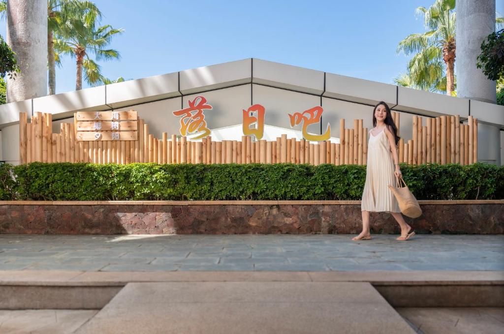 a woman in a dress standing in front of a building at Ocean Sonic Resort Sanya in Sanya