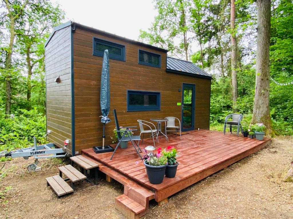 una pequeña casa en el bosque con una terraza de madera en La Tiny House de Nanou, en Rochefort