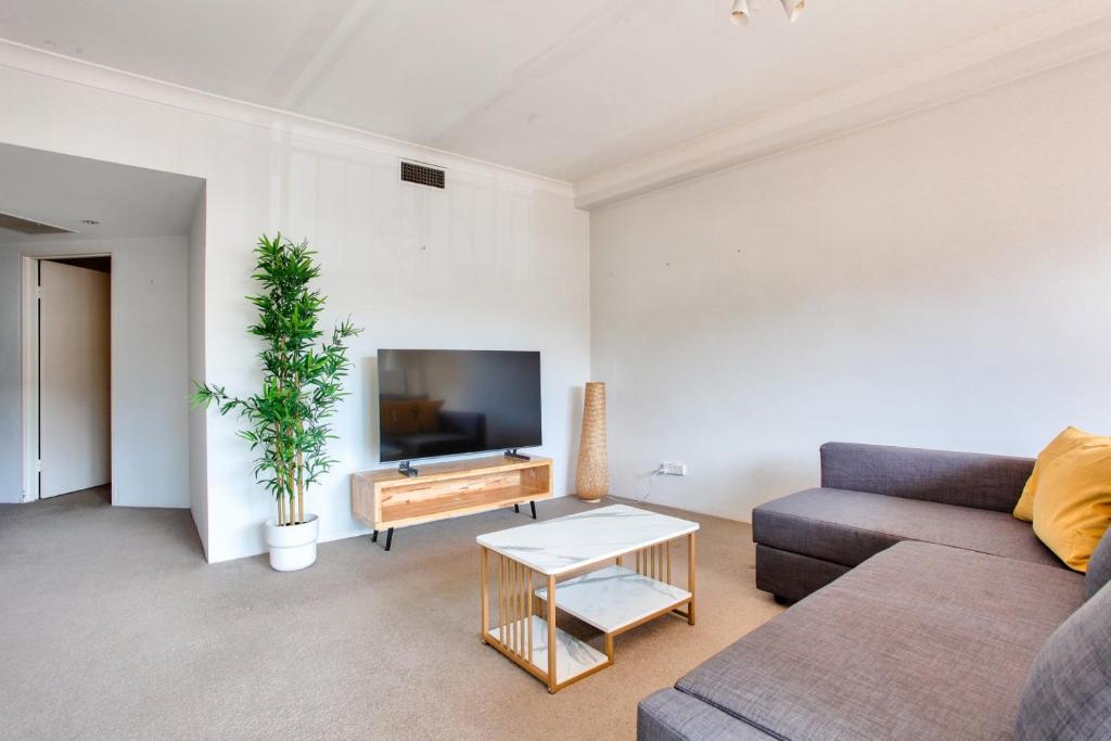 a living room with a couch and a tv at Cozy 2 Bedroom Apartment Surry Hills in Sydney