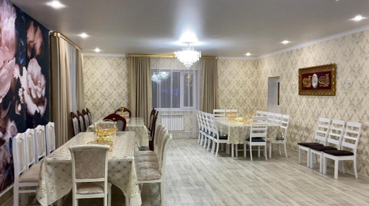een eetkamer met tafels en stoelen en een kroonluchter bij Коттедж in Borovoye