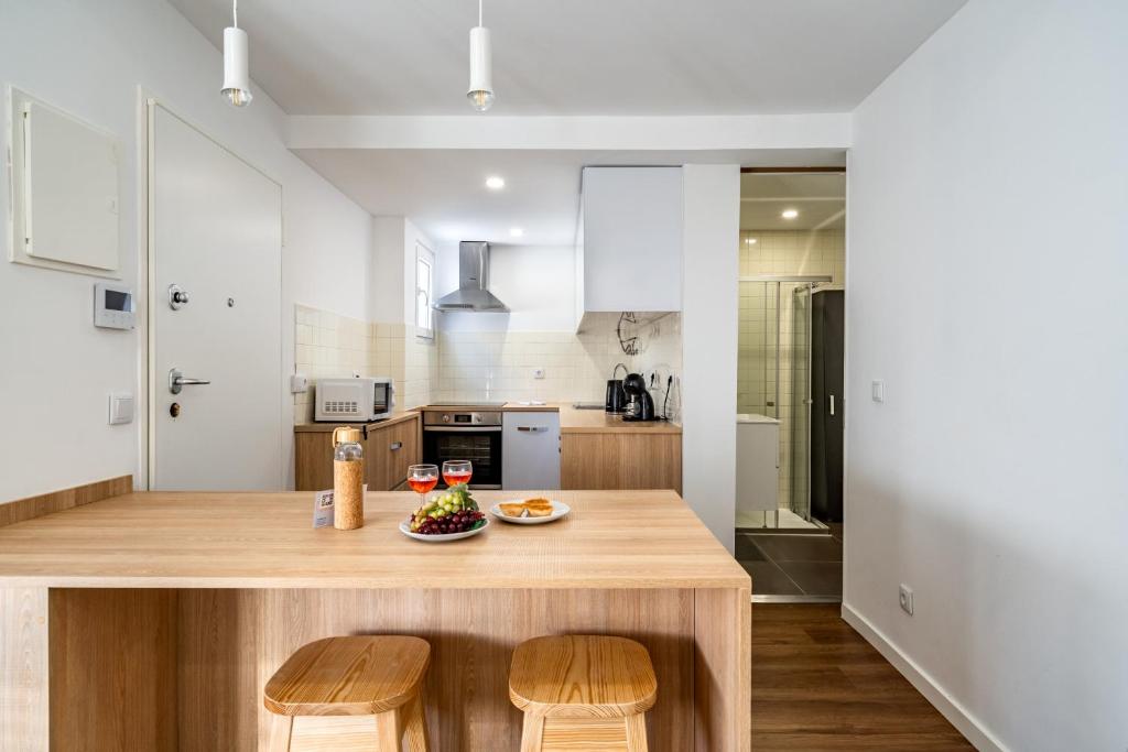 a kitchen with a table with a bowl of fruit on it at Almada Cityscape Apartment in Almada