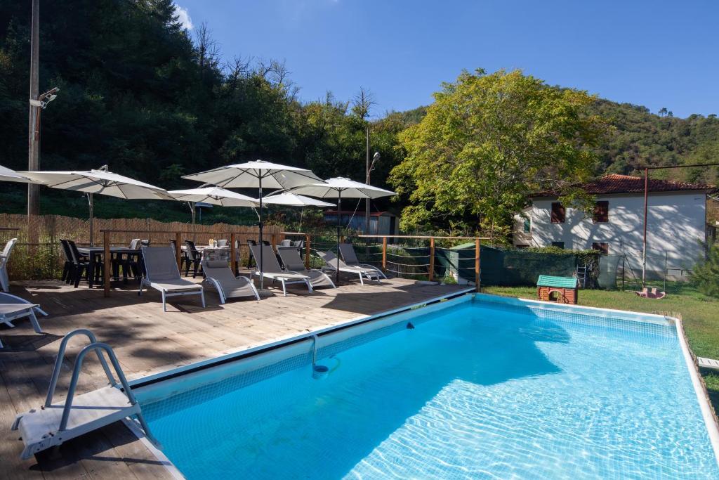 a swimming pool with chairs and tables and umbrellas at Appartamenti - Here&Now in front of The Castle in Tresana