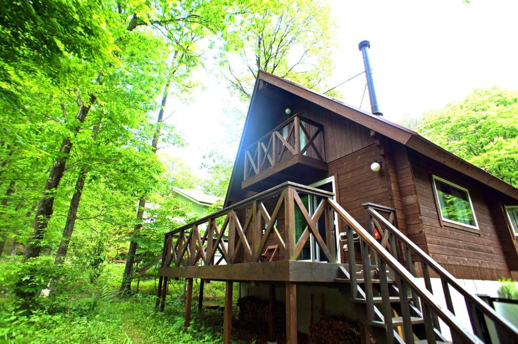 una cabina nel bosco con un ampio ponte di HARUNA LODGE Private log house with starry sky from the skylight, fireplace, and spacious deck BBQ a Nasu