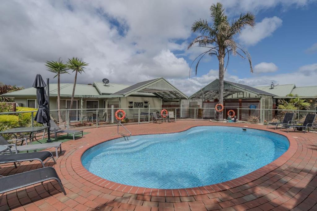 a large swimming pool with chairs and a palm tree at Relaxed Poolside Living in a Resort-style Setting in Safety Beach