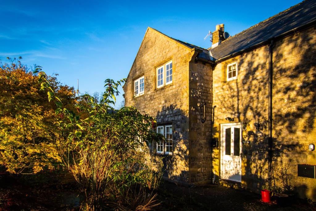 um velho edifício de tijolos com uma porta branca em Acer Holiday Cottage Tideswell village Buxton Peak District by Rework Accommodation em Tideswell