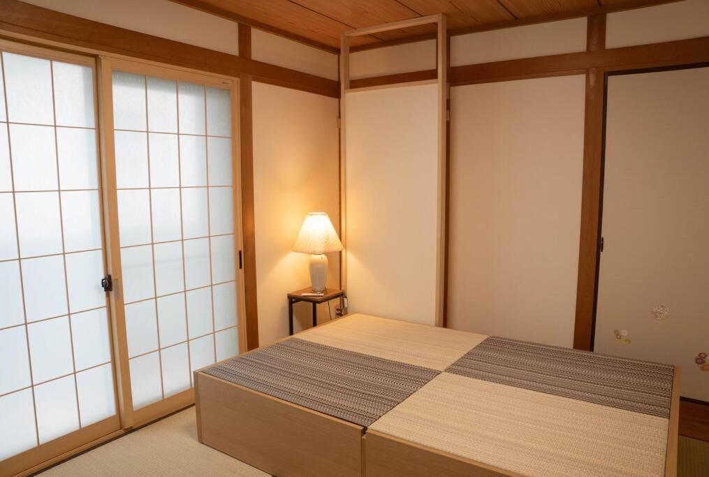 ein Schlafzimmer mit einem Bett und einer Lampe in der Unterkunft ミセスマルベリー in Utazu