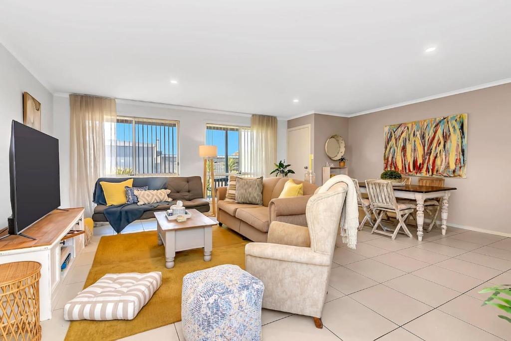 a living room with a couch and a tv at Shore Haven - A Relaxed Seaside Stay in Port Noarlunga
