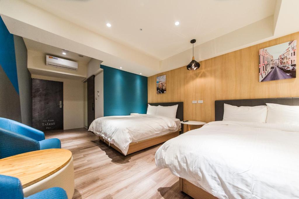 a hotel room with two beds and a blue wall at Talent Hotel E Series in Luodong