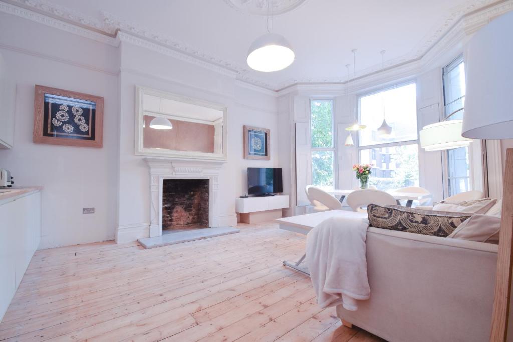 a living room with a couch and a fireplace at Stylish 2BR Designer Flat Holland Park in London