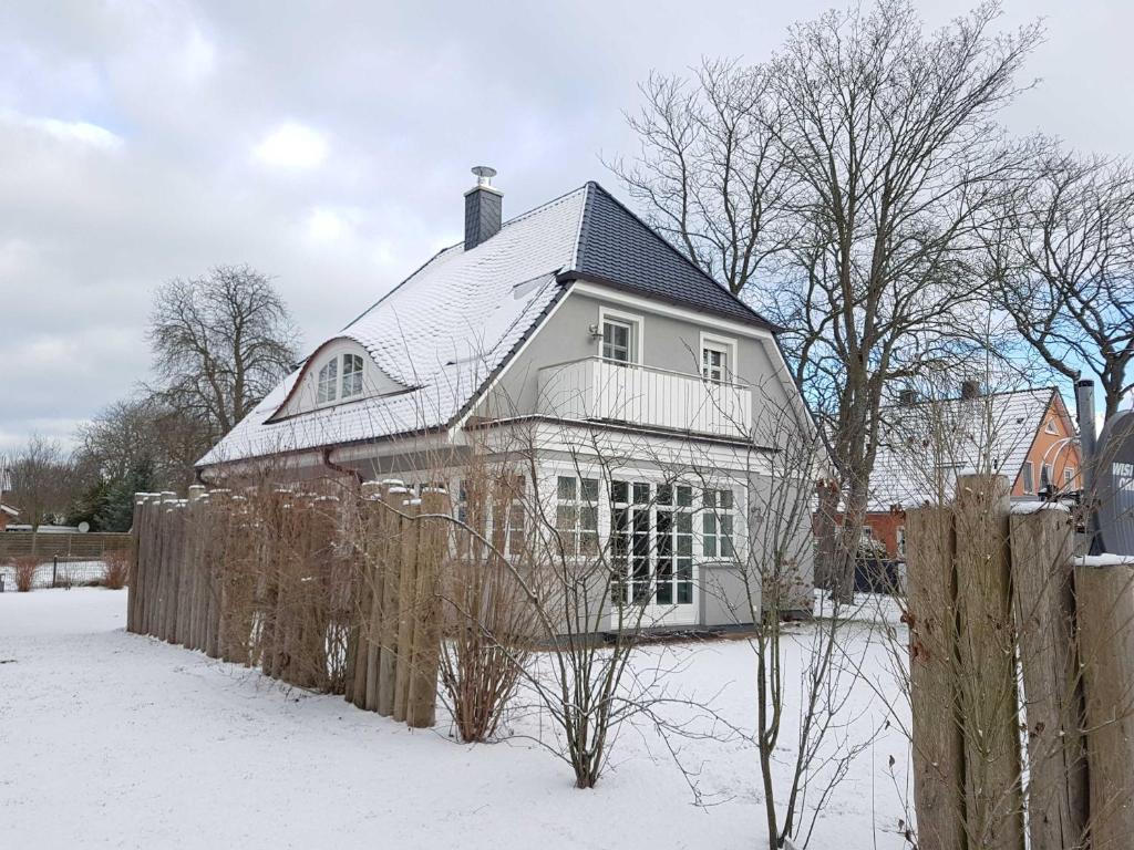 une maison blanche avec une clôture dans la neige dans l'établissement Haus "Fock", à Prerow