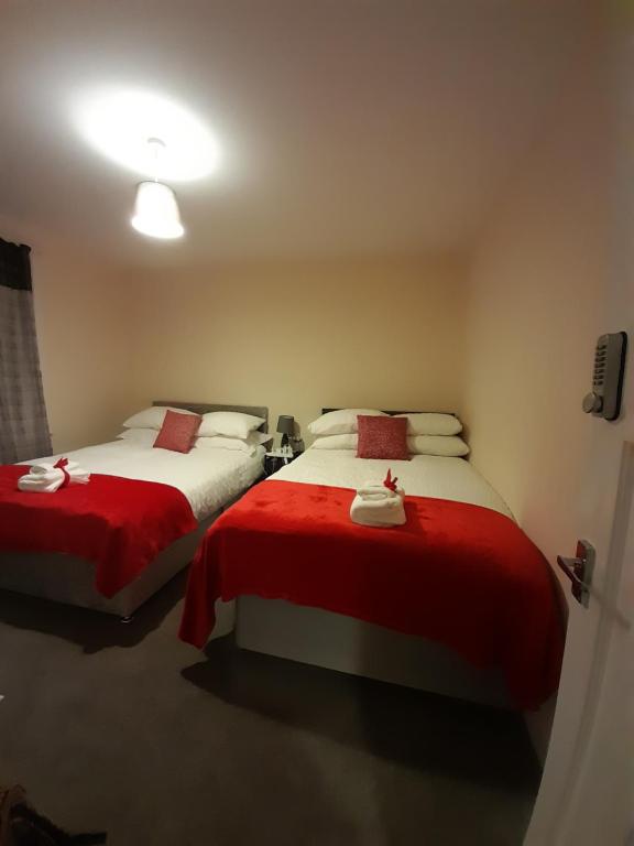 two beds in a room with red and white sheets at Matipa-Rise Guest House Southampton in Southampton