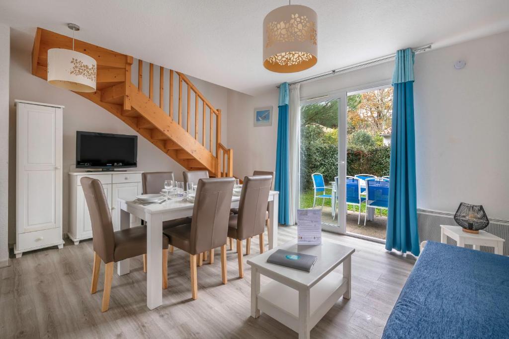 ein Esszimmer und ein Wohnzimmer mit Tisch und Stühlen in der Unterkunft 400m de la plage des Sables d'Or - Maison pour 8 in Le Pointeau