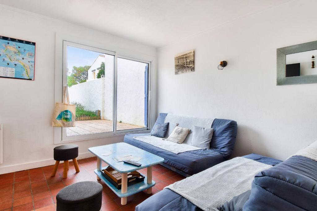 un salon avec un canapé bleu et une fenêtre dans l'établissement Instants de détente et de partage aux sables d'or, à La Guérinière