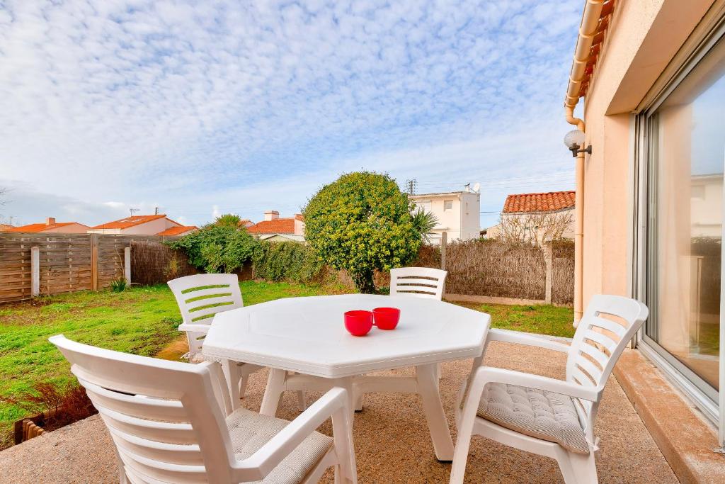 une table blanche et des chaises sur une terrasse dans l'établissement Bretignolles-sur-mer - 450m de la plage, à Bretignolles-sur-Mer