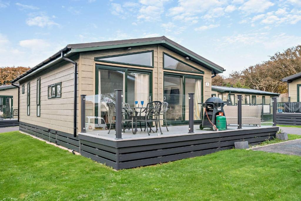 a small house with a large deck in a yard at Belvedere Lodge, Shorefield Country Park, Shorefield Rd, Milford on Sea, Lymington SO41 0LH in Lymington