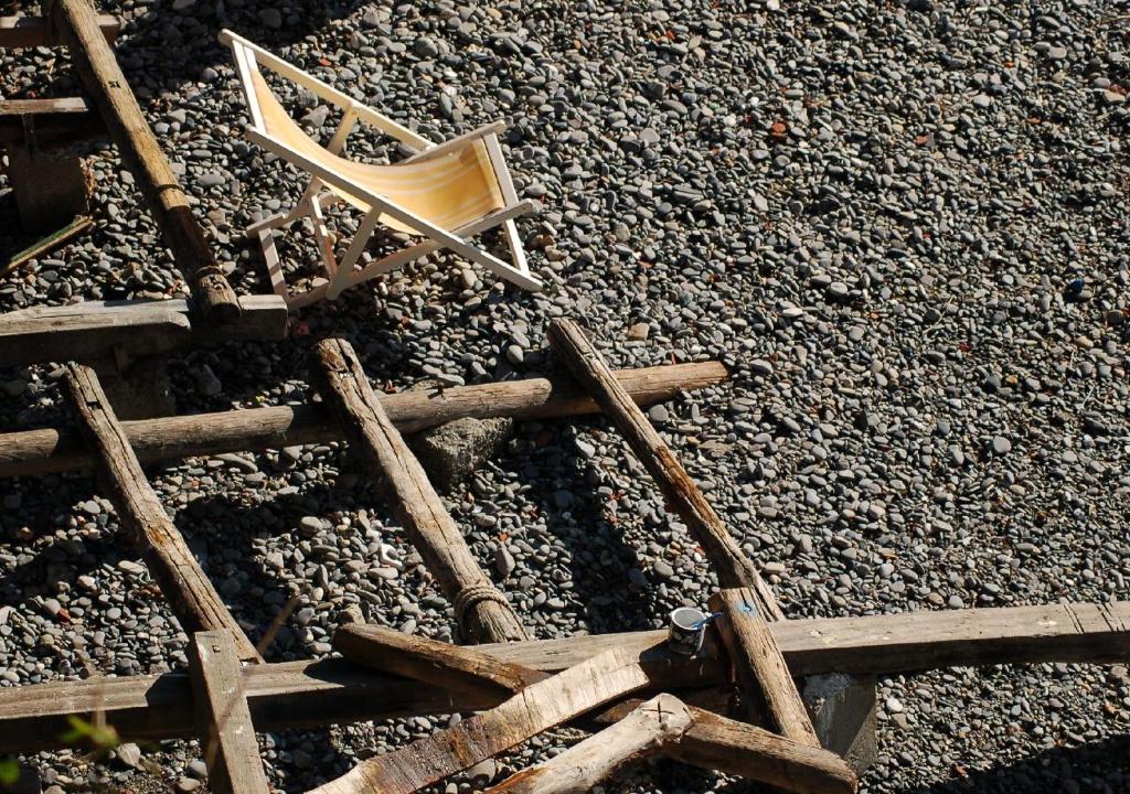 an old wooden chair sitting on a pile of rocks at Casa dell'Arco Civico 35 in San Fruttuoso