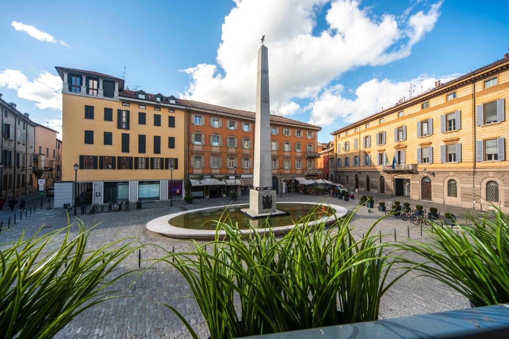 a square with a monument in front of buildings at Reggio Center Lovely Rooms in Reggio Emilia