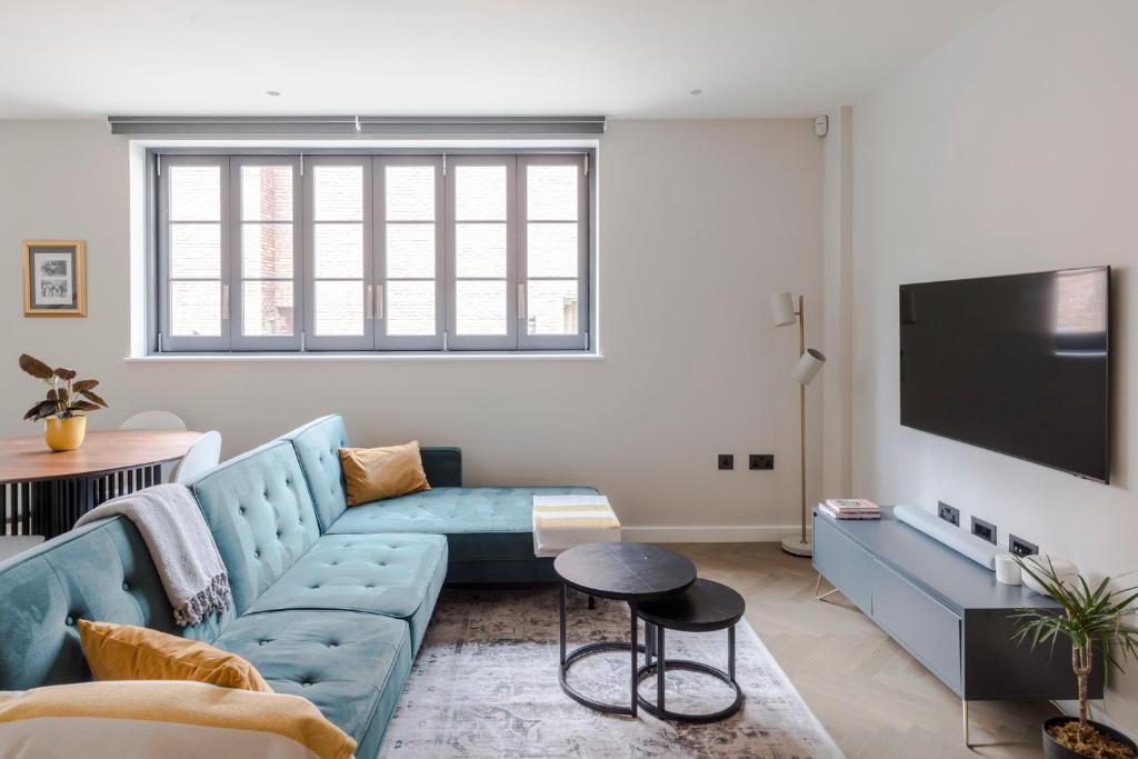 Il comprend un salon doté d'un canapé bleu et d'une télévision à écran plat. dans l'établissement The Tranquil Den - Regent's Park - by Frankie Says, à Londres