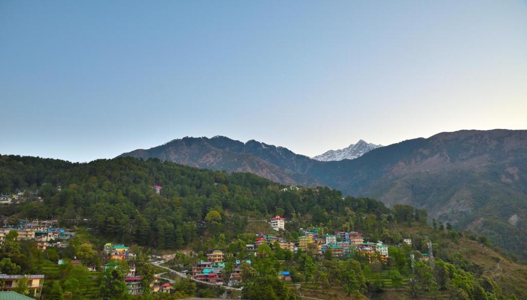 a town on a hill with mountains in the background at Hotel Nature View near Mall Road in Dharamshala