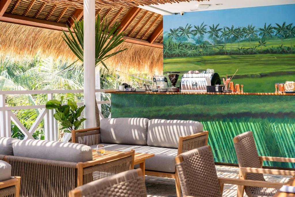 a patio with a couch and chairs and a bar at IZE Canggu by LifestyleRetreats in Canggu