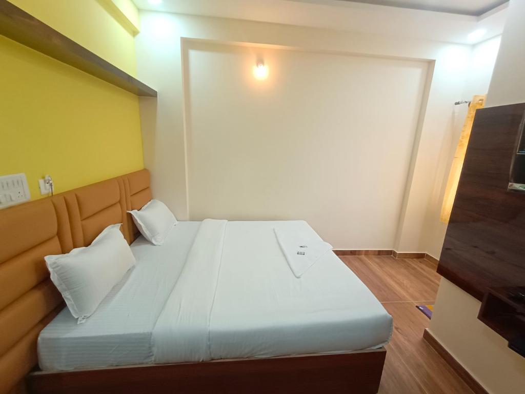 um quarto com uma cama grande com lençóis brancos e almofadas em STAYMAKER Karanji Paradise - Next to Liquor station em Bangalore