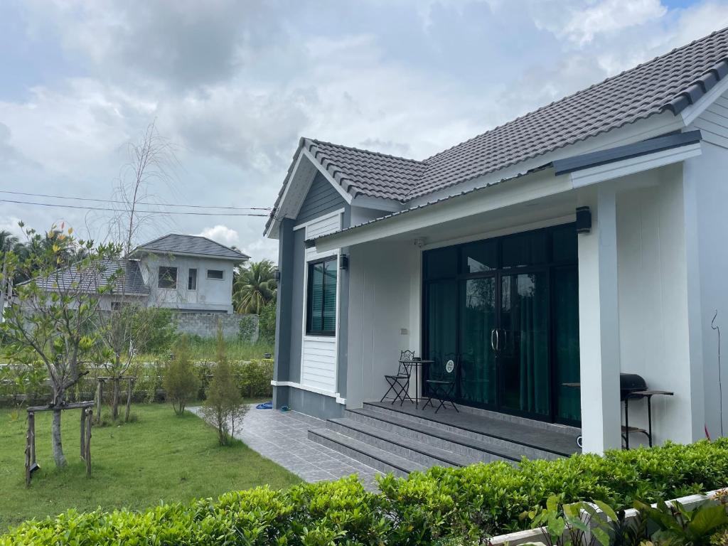 uma casa branca com um alpendre e um quintal em Baan pakiet&Khun jang em Ban Nam Lai Ta Tum