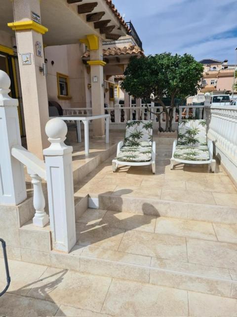 duas cadeiras brancas sentadas num alpendre de uma casa em Villa San Jose II Townhouse em Cabo Roig