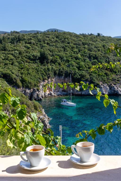 two cups of coffee on a table with a boat in the water at Costa Smeralda in Syvota