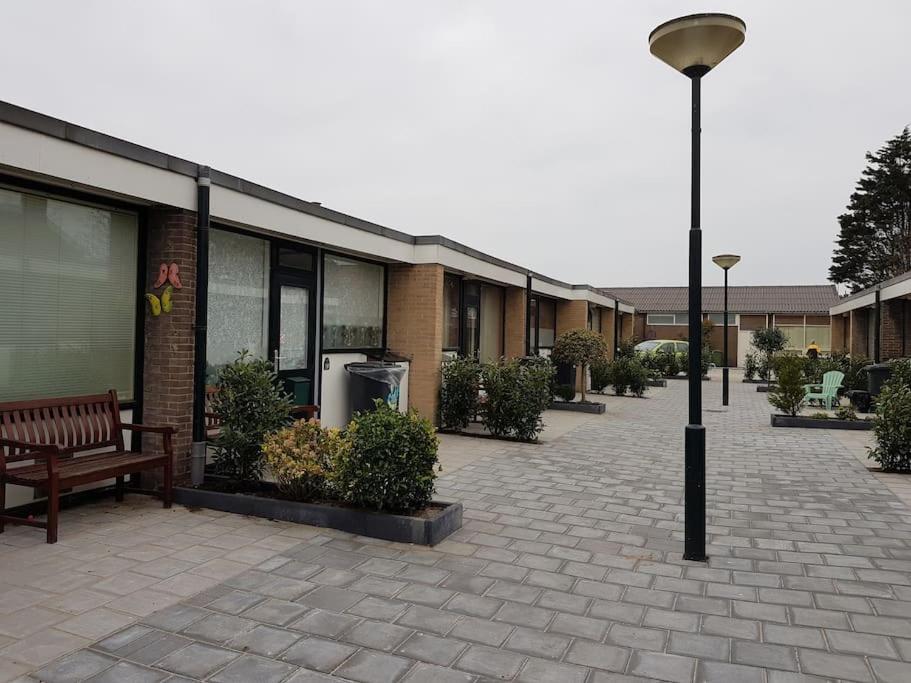 a building with a bench and a street light at Zomerhuisje 18K - 1 km van het strand in Wijk aan Zee