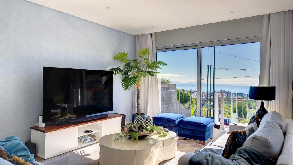 a living room with a tv and a large window at 24, The Townhouse by LovelyStay in Funchal