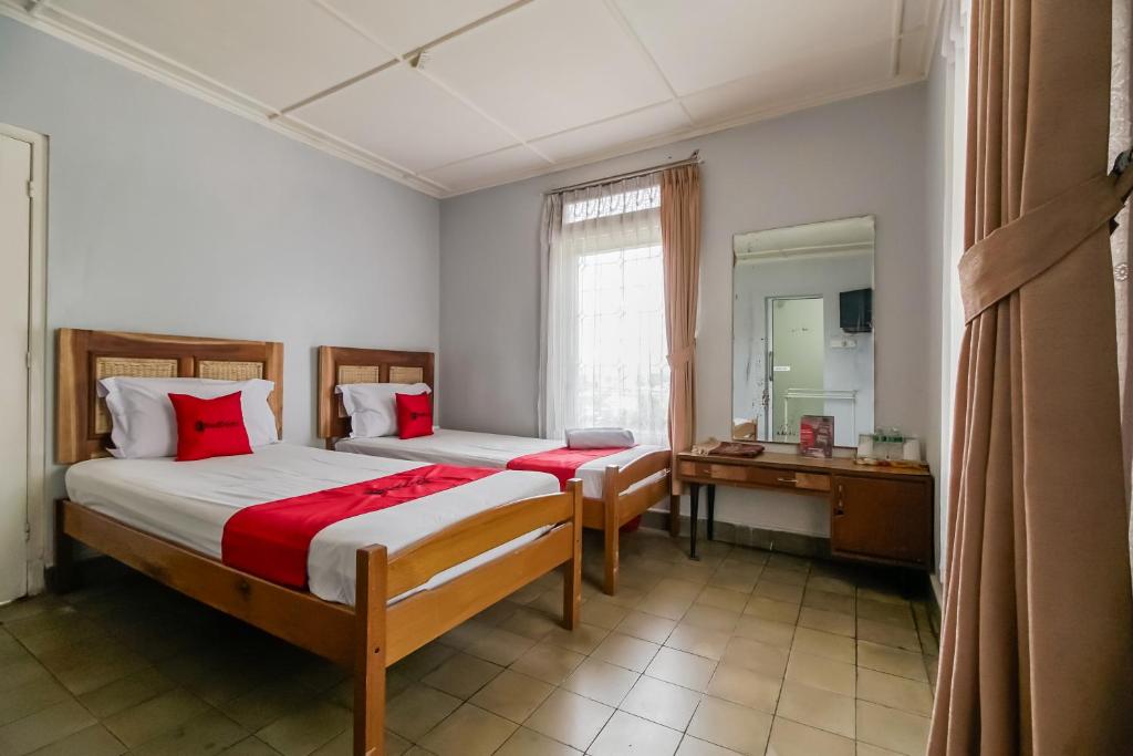 a bedroom with two beds and a mirror and a sink at RedDoorz near Jam Gadang Syariah Bukit Tinggi in Bukittinggi