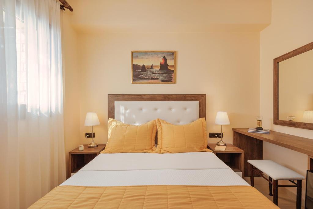 a bedroom with a bed and two lamps and a mirror at Costa Smeralda in Syvota