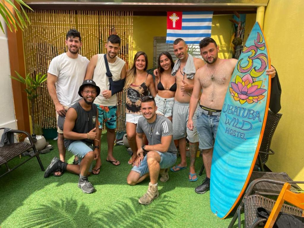 a group of people posing for a picture with a surfboard at Ubatuba Wild Hostel in Ubatuba