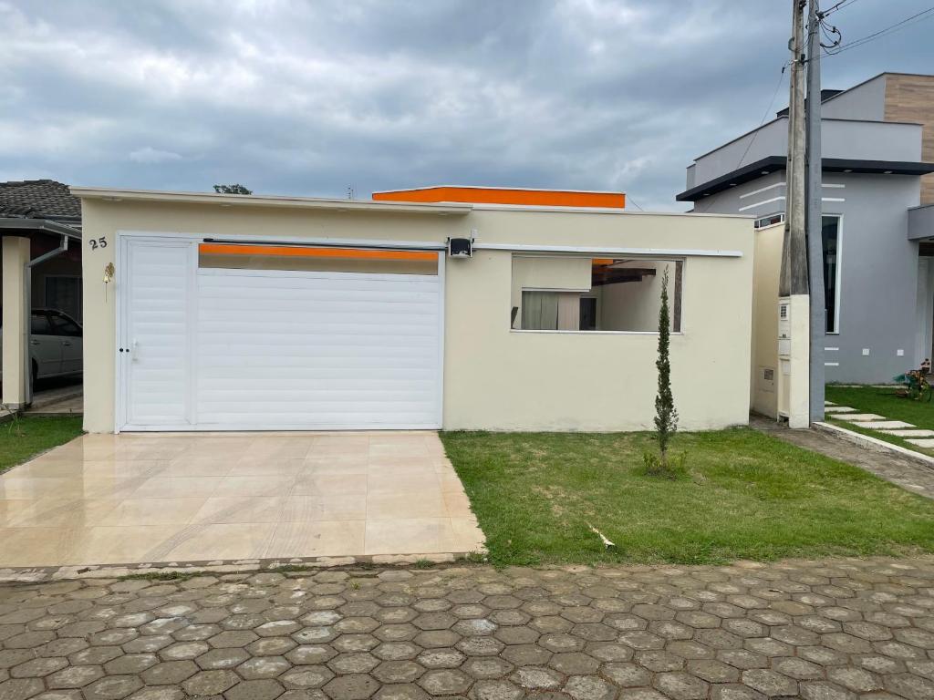 un garage blanc avec un toit orange dans l'établissement Casa com piscina em condomínio, à Cachoeira Paulista