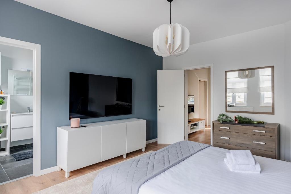 a bedroom with a white bed and a flat screen tv at Evere EU Residence in Brussels